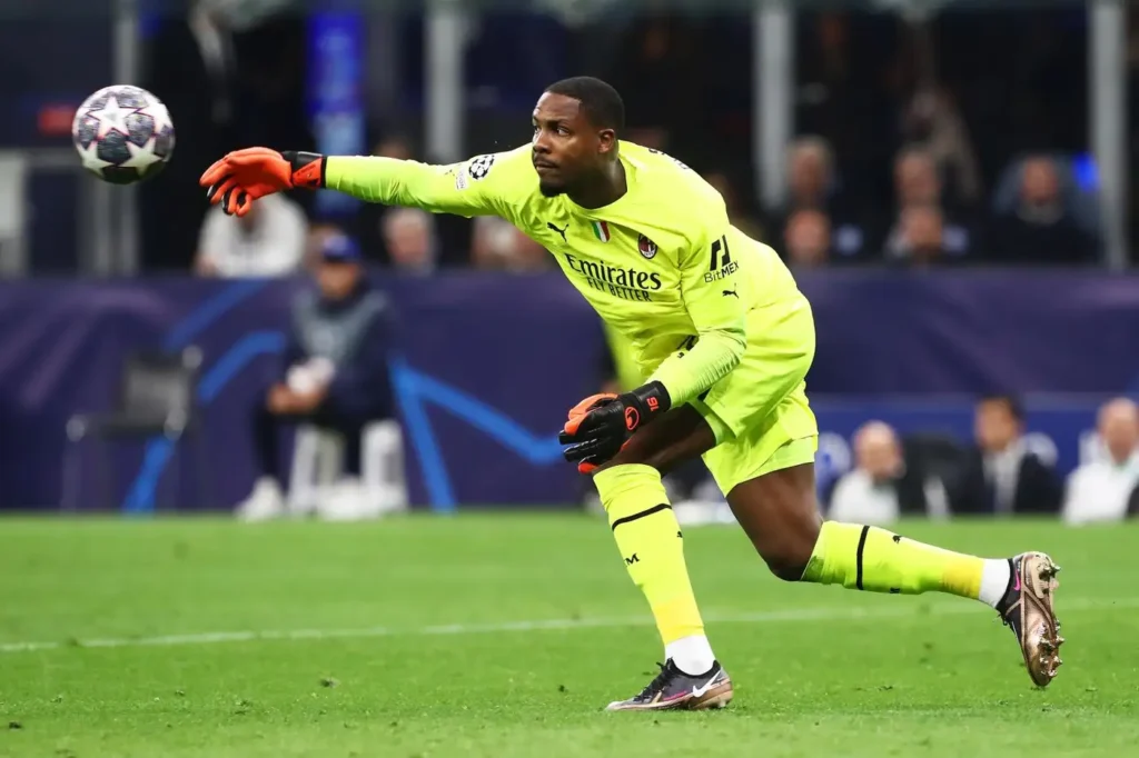 Mike Maignan in maglia giallo fluorescente che rilancia il pallone durante una partita di Champions League